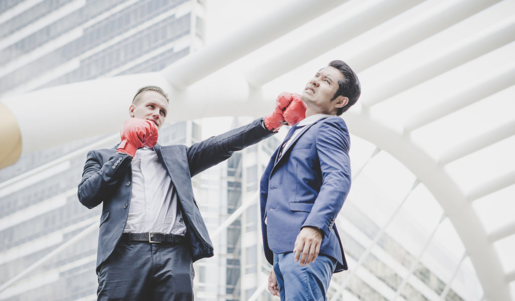 Businessman with red boxing gloves ready to fight his coworker.