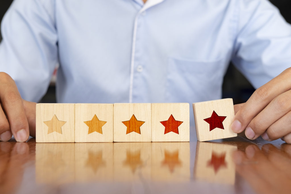 asx-200-asx-apt-afterpay-Businessman hand putting wooden five star shape on table.